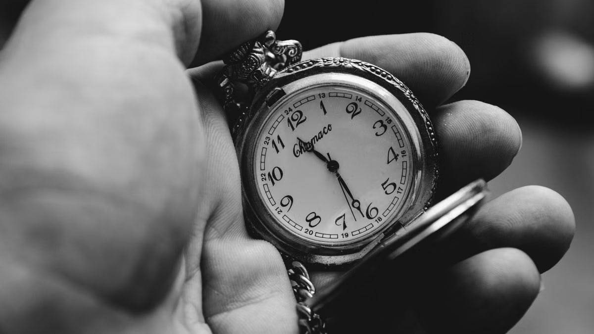 Black and white photo of a classic pocket watch in hand, showing time and elegance.